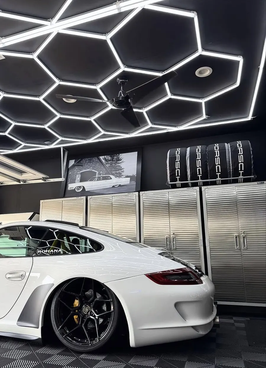 Large hex grid on a black garage ceiling over a white Porsche
