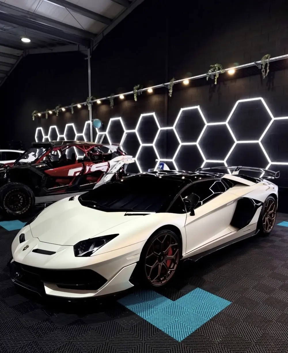 Hex lights mounted on a black wall behind a white Lamborghini