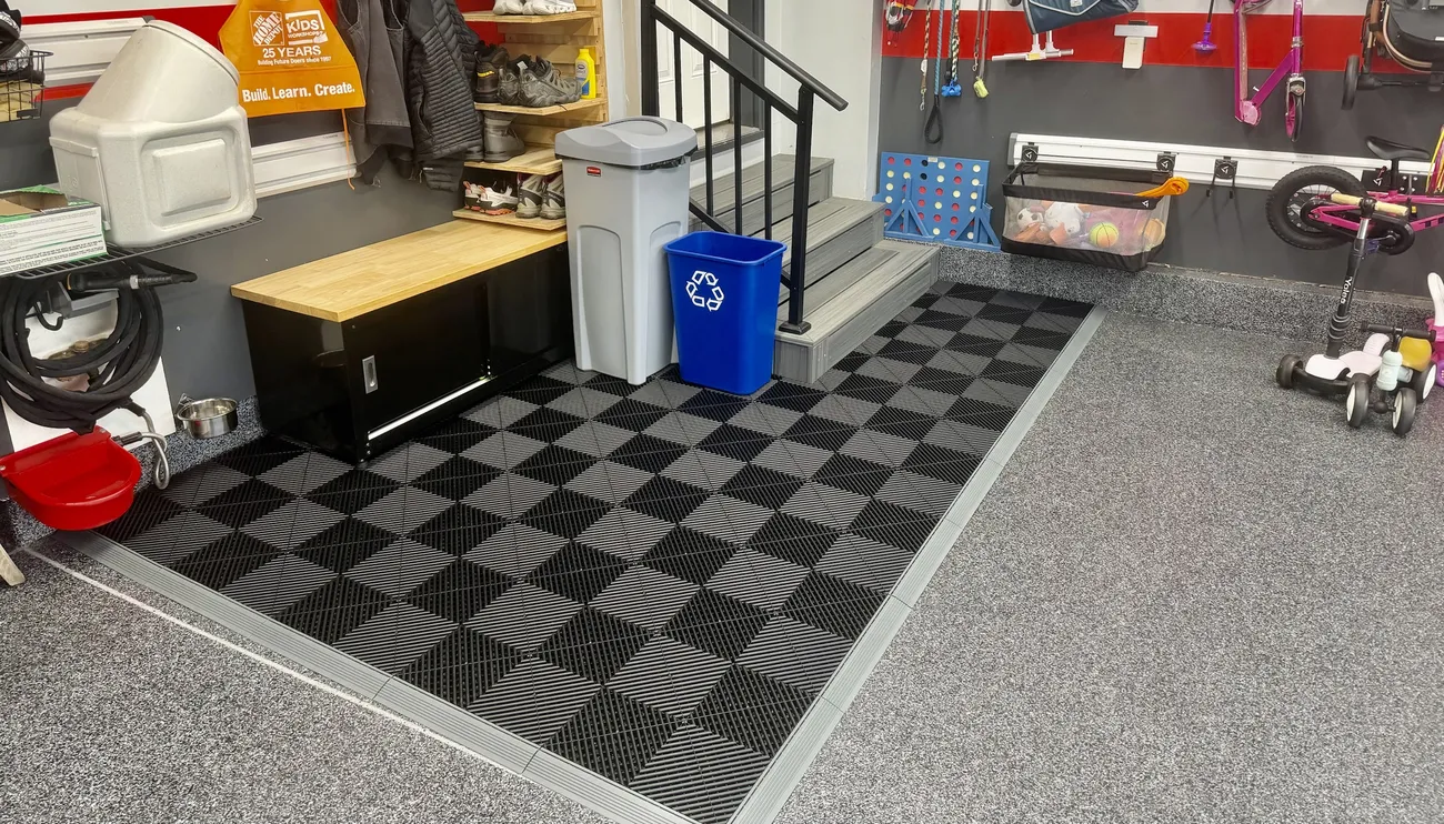 Black and gray Swisstrax pad with gray edging at the bottom of garage stairs