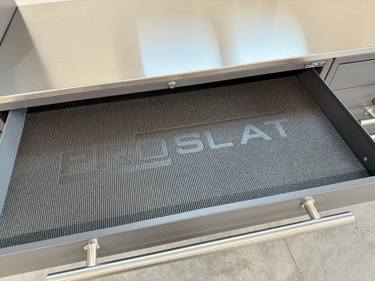 Open Lux drawer with a Proslat liner under a stainless steel top